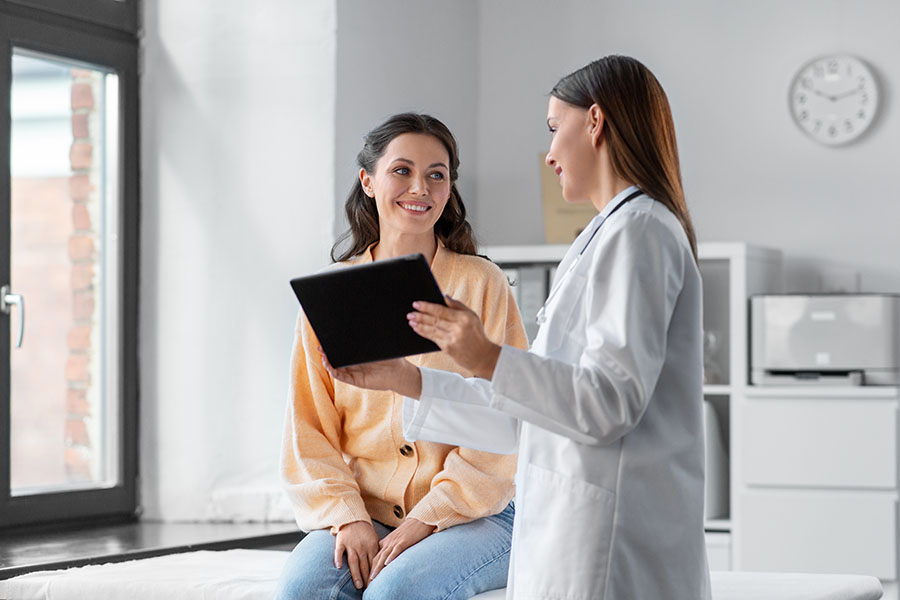 female doctor with tablet pc and woman at hospital